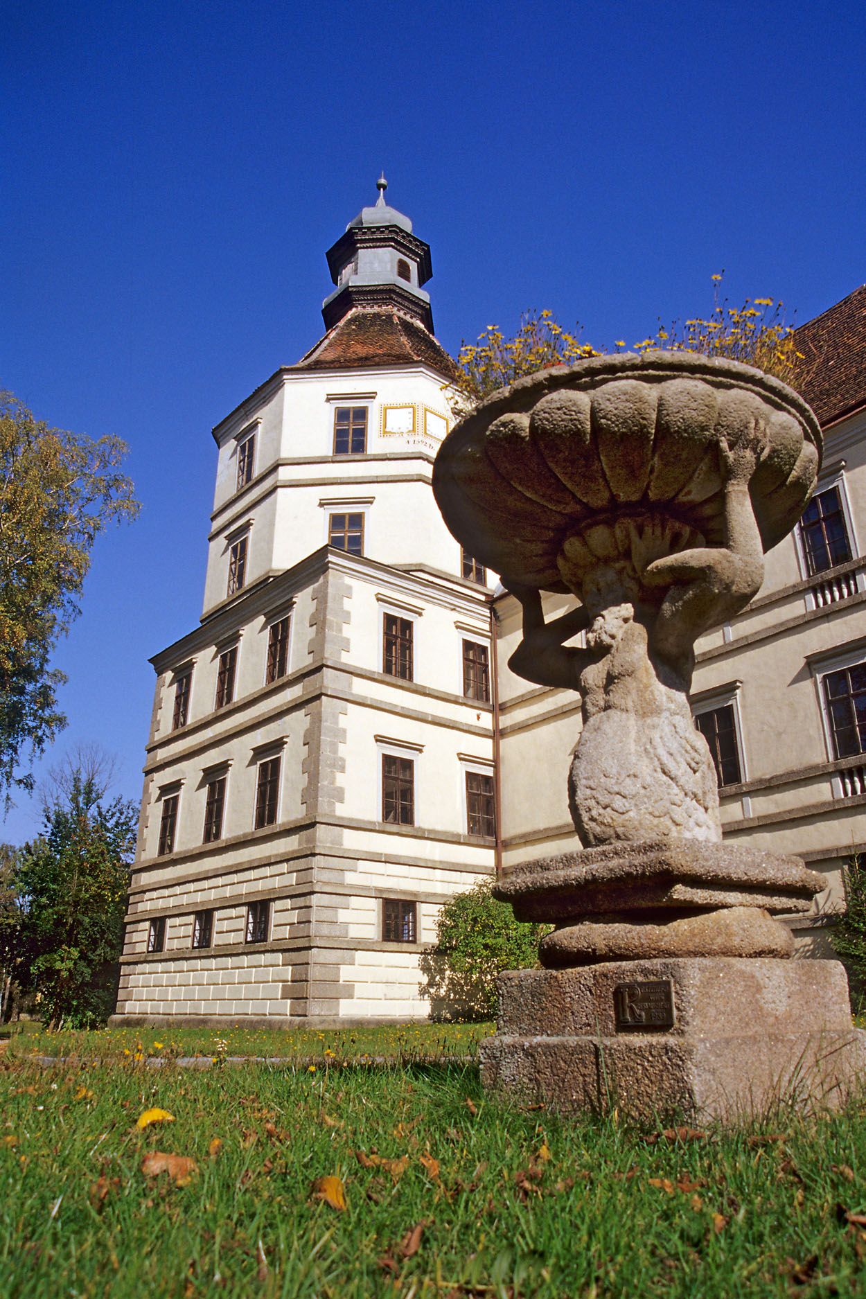 A historic building with a tower and a stone statue in the foreground.