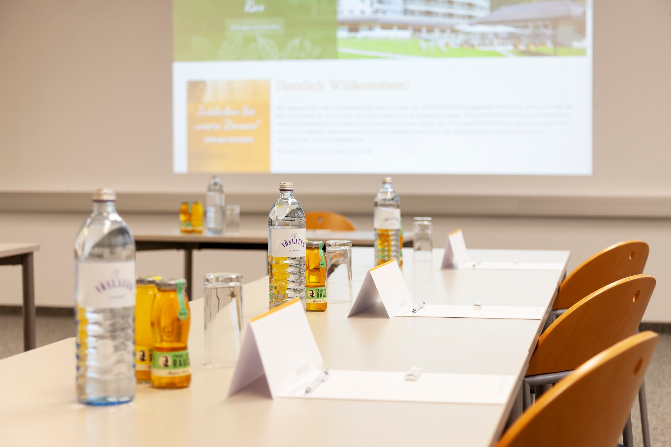 Seminar room with tables, chairs, water bottles and notepads.