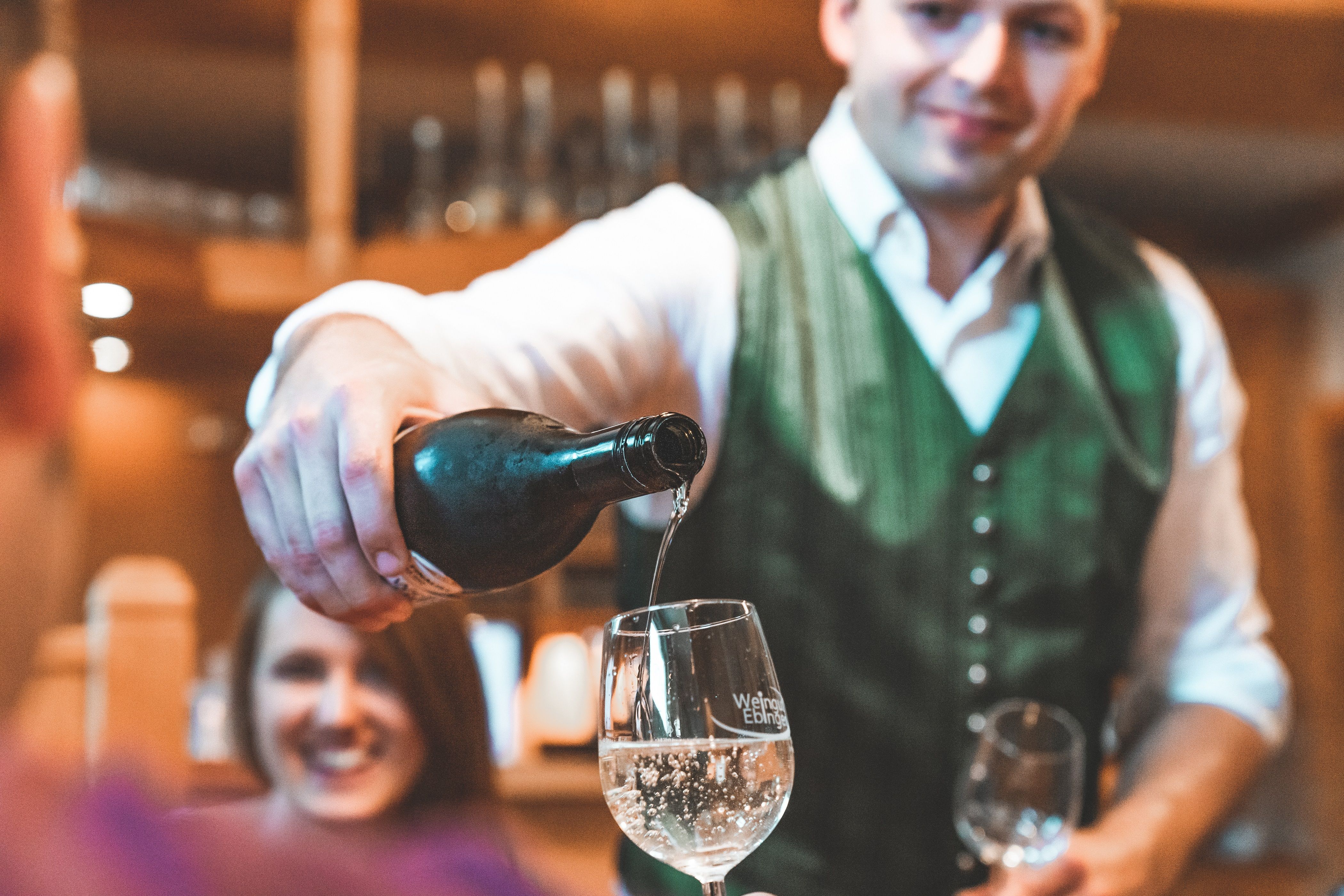 A man in traditional dress pours wine into a glass.