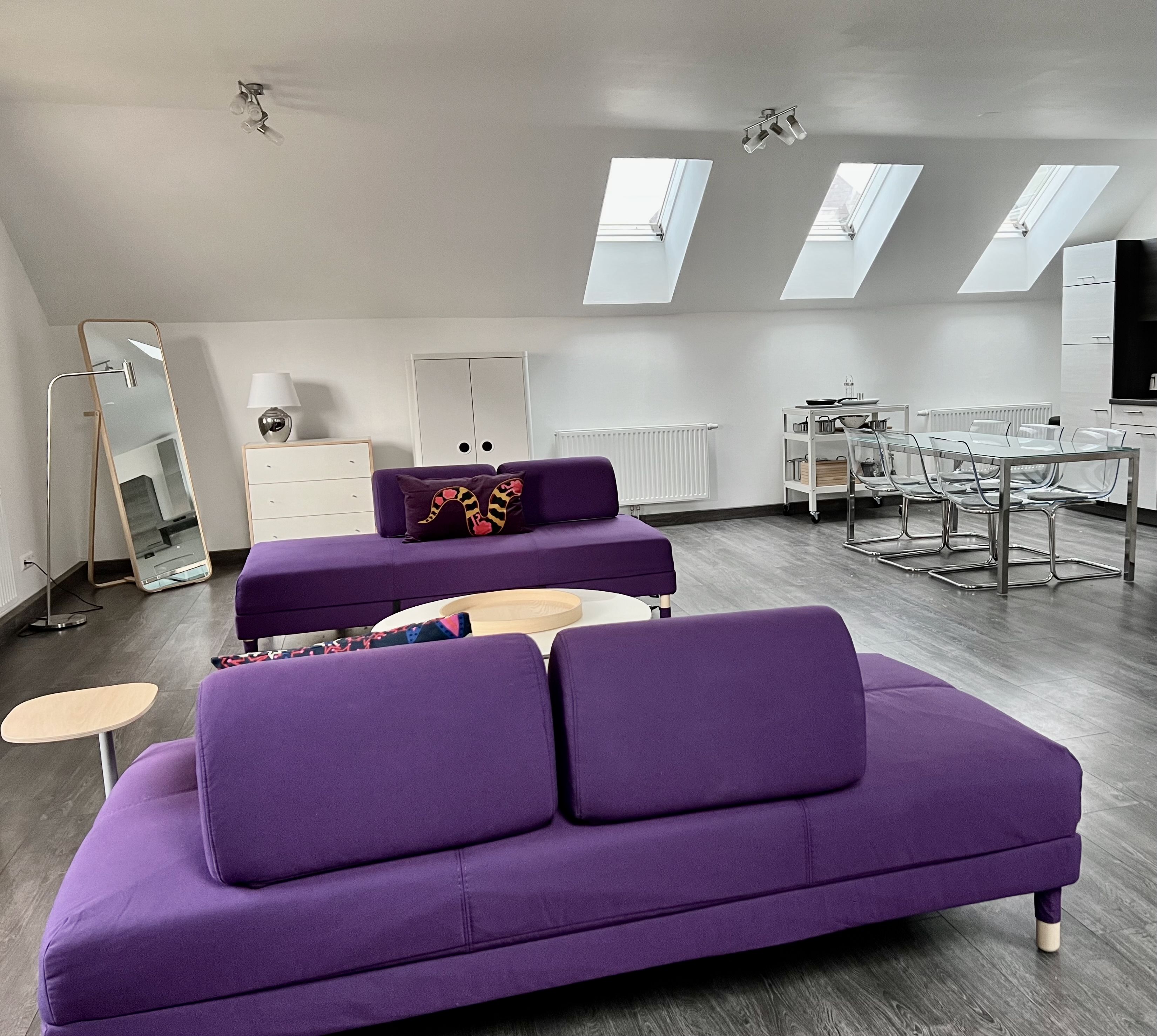 Modern loft with purple sofas, dining table and skylights.