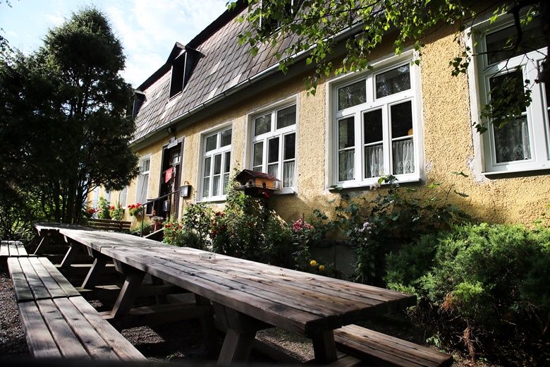 Yellow building with white windows and long wooden benches in the foreground.