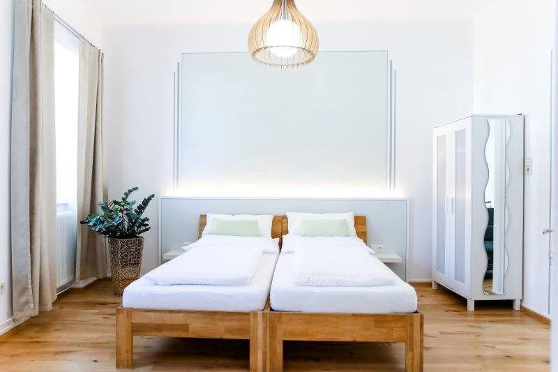 Modern guest room with two single beds, a closet and a plant.