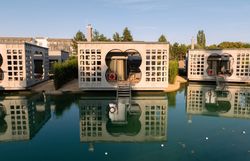Modern villas on water with reflective facades and stairs, surrounded by nature.