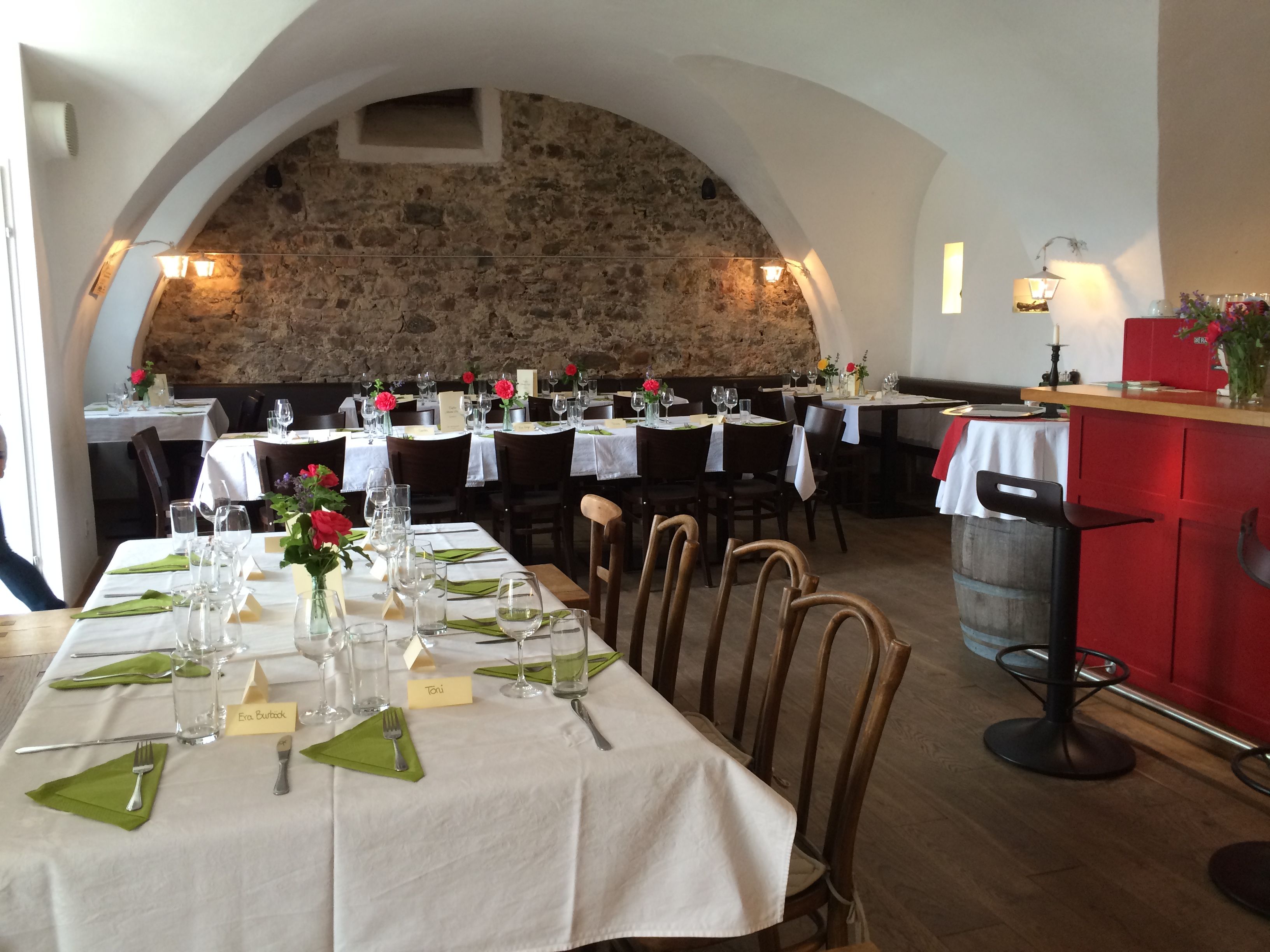 Cozy dining room with covered tables, stone wall and vaulted ceiling.