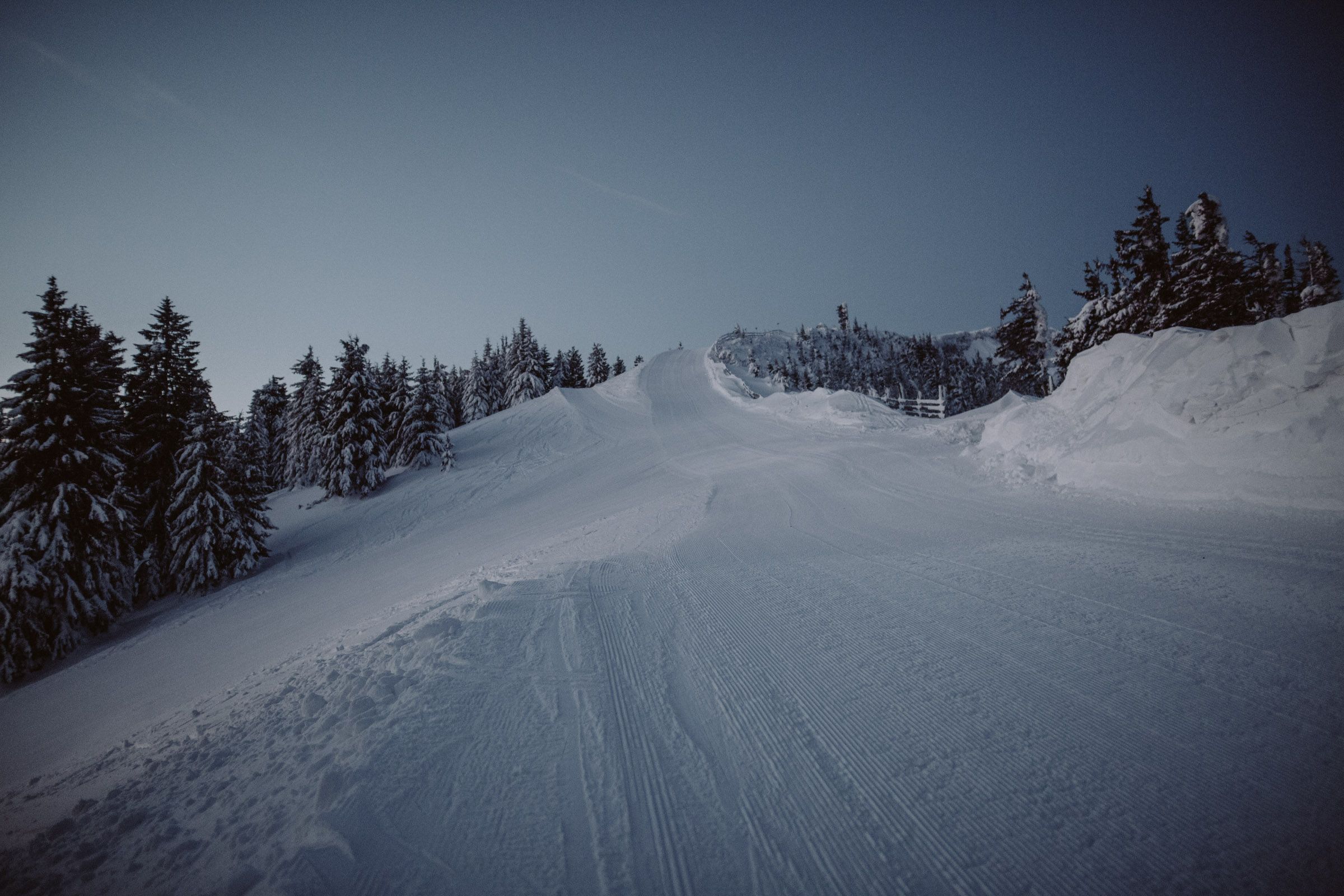 Snow-covered ski slope in the Unterberg ski area at dusk.