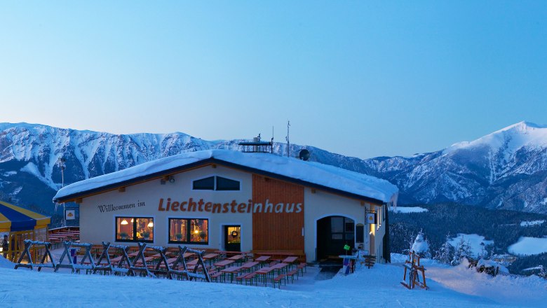 Winter landscape with Liechtensteinhaus and cable car in front of snow-covered mountains.