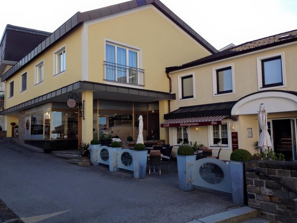 Yellow building with café and terrace, Schüller lettering visible.