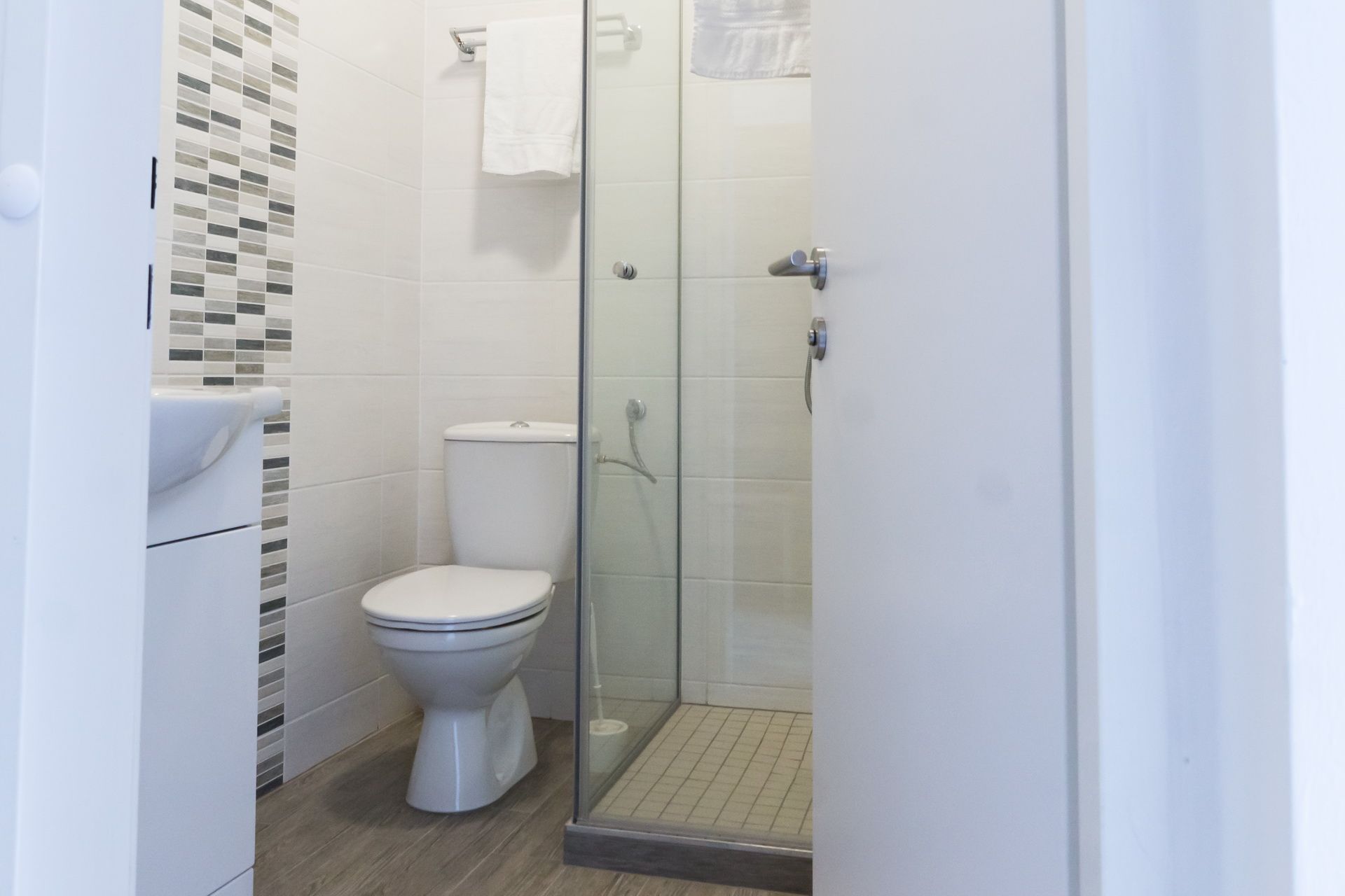 Modern bathroom with toilet, shower and towel rail.