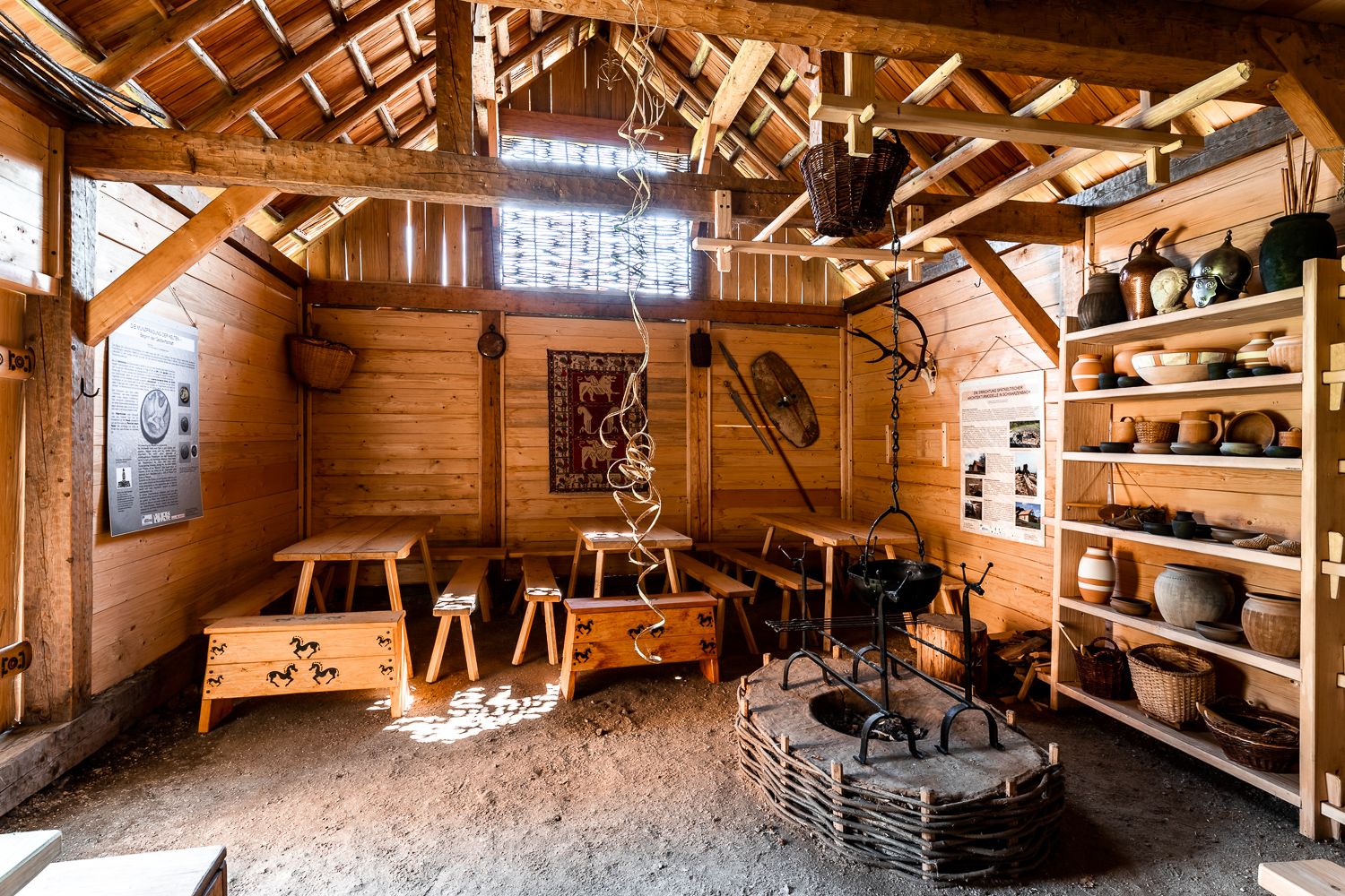 Interior view of a reconstructed Celtic house with wooden furniture and pottery.