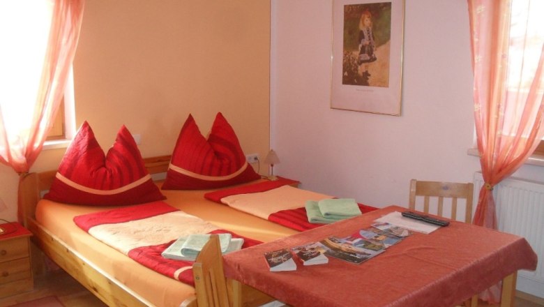 Sleeping area at the Horak, © Hubert Horak Cozy bedroom with double bed, red pillows and table with brochures.