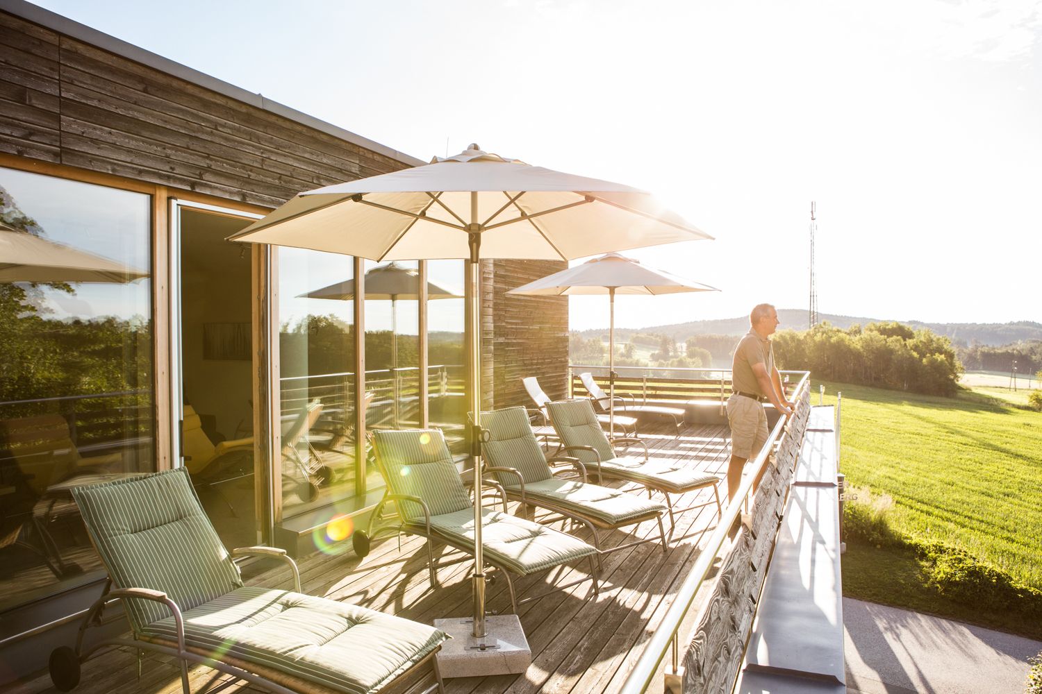Sunny roof terrace with sun loungers and parasols, with a view of the countryside.