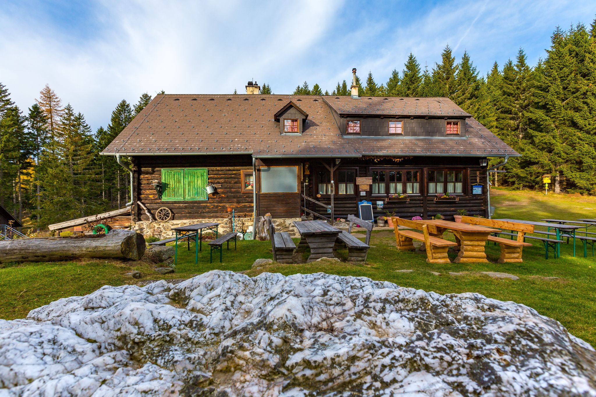 Wooden hut with outdoor tables, surrounded by forest.