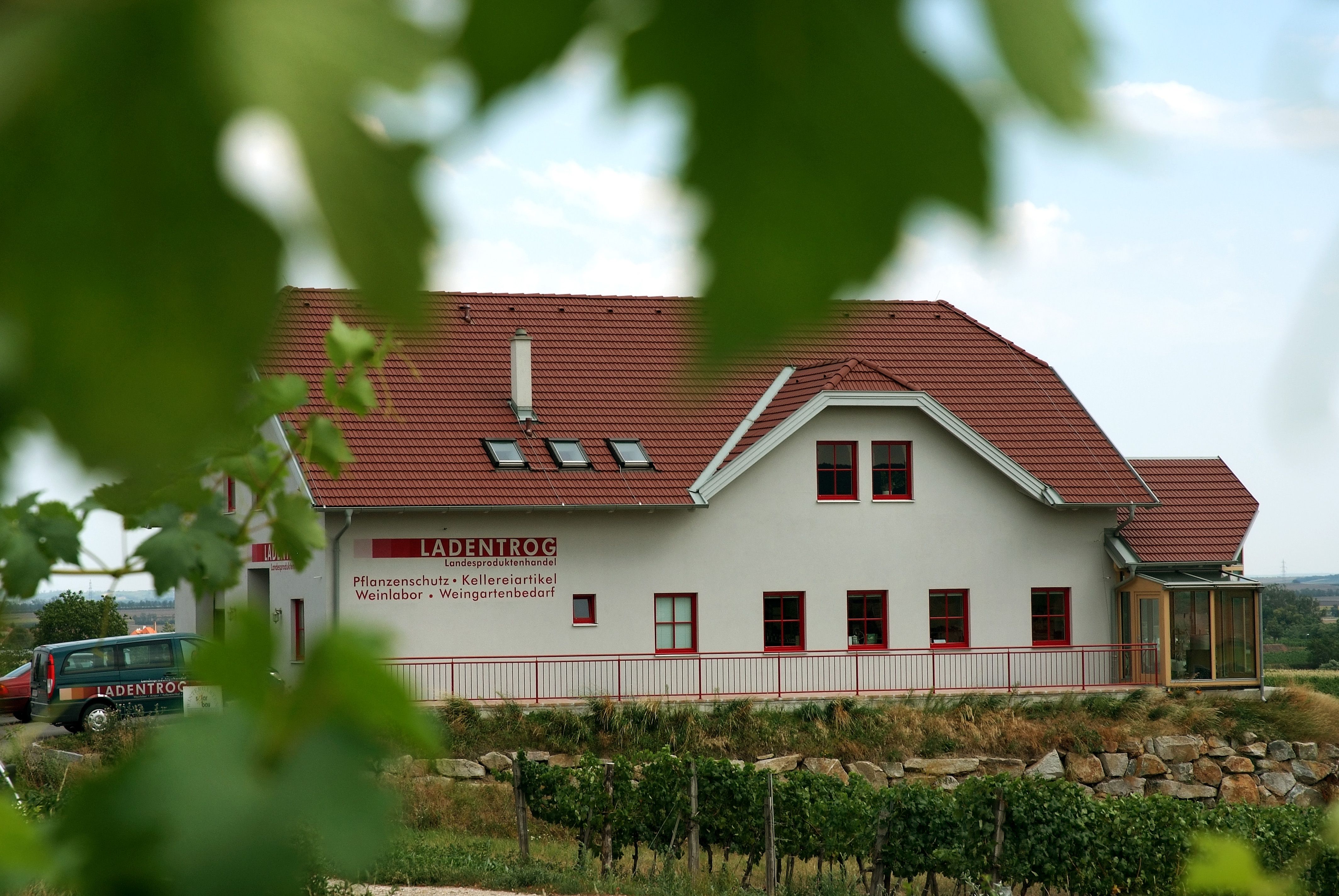 Building with red roof and 'LADENTROG' lettering in a rural setting.