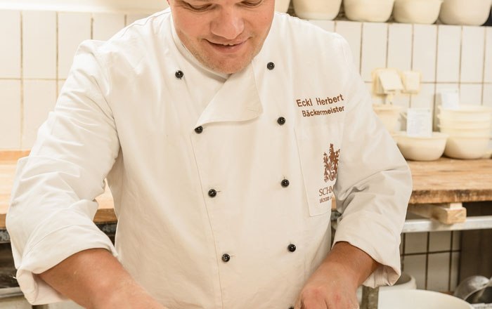 A master baker forms dough in a bakery.