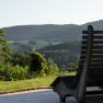 Wooden bench with a view of the hilly landscape and trees in the background.