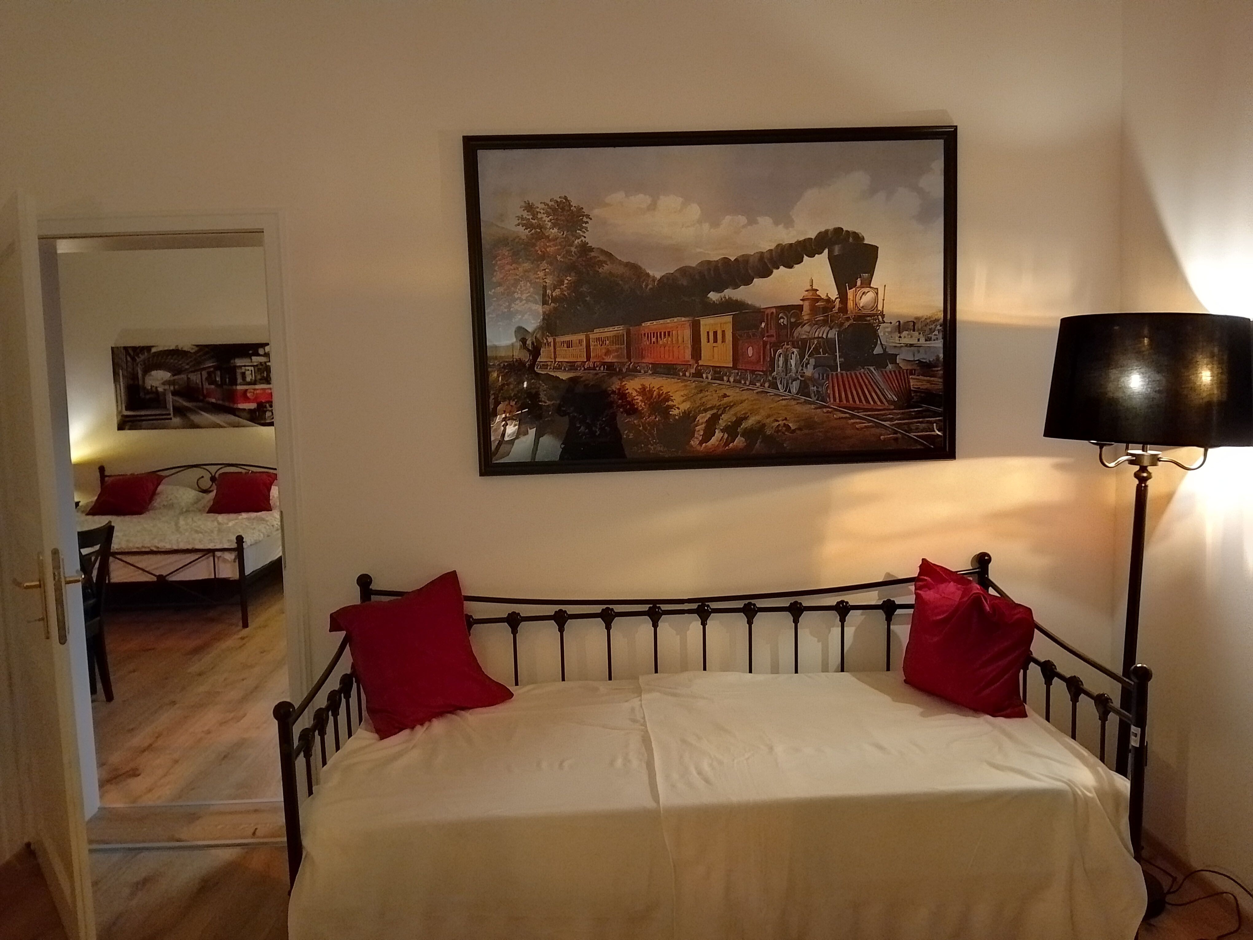 Room with railroad decor, bed and lamp.