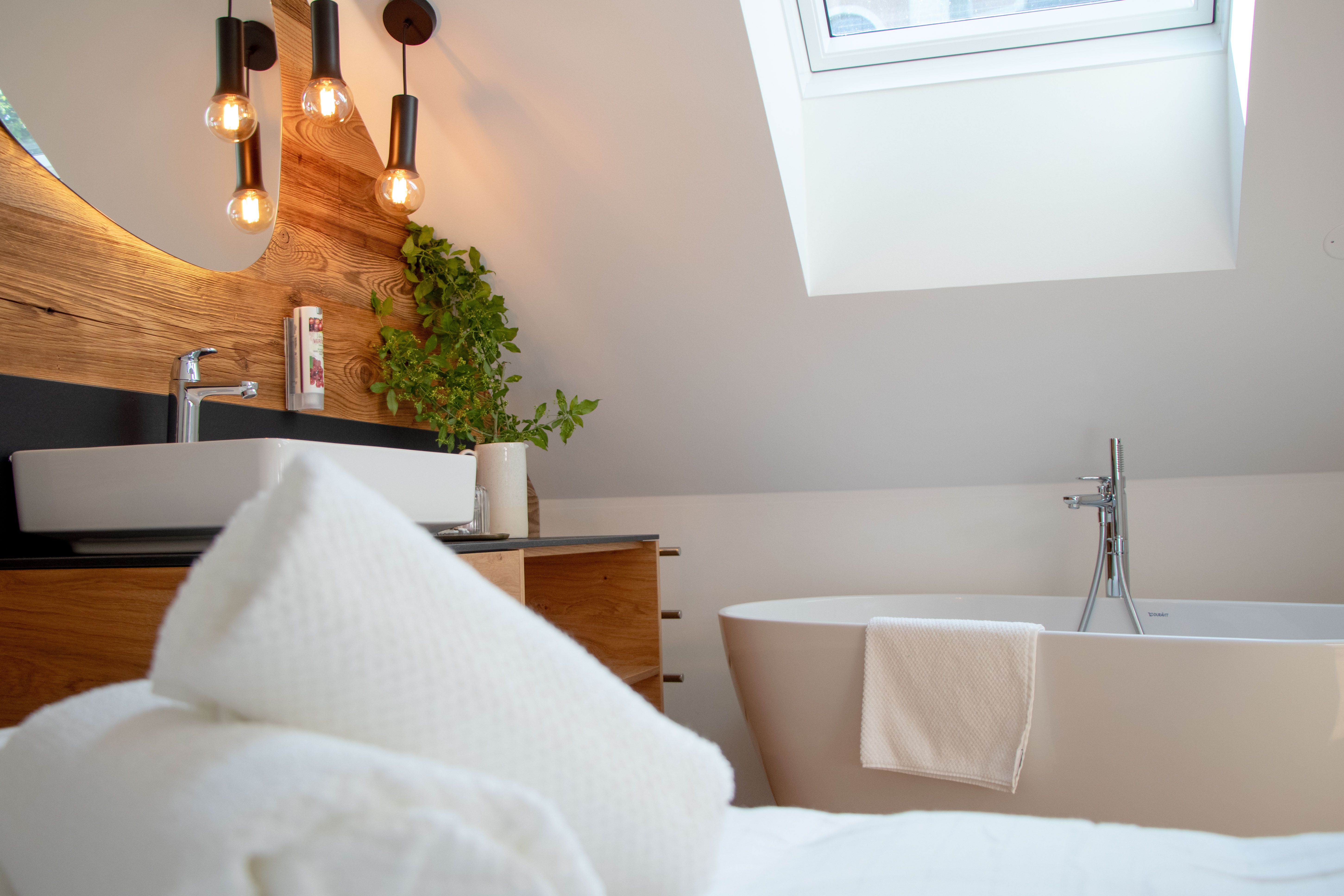 Modern bathroom with bathtub, washbasin, plants and skylight.