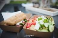Quinoa salad with vegetables and bread served in paper bowls.