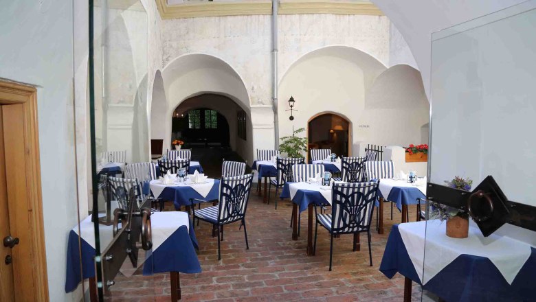 Inner courtyard of a restaurant with laid tables and striped chairs.