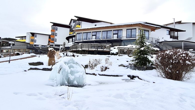 Snow-covered hotel building with frozen fountain in the foreground.