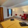 A bedroom with double bed, yellow bed linen, wooden wardrobe, red armchair and white sofa.