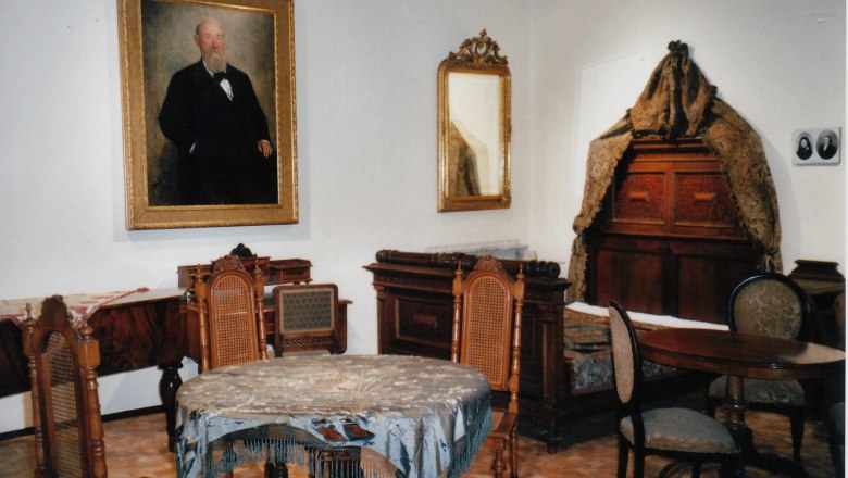 Historic room with antique furniture and a painting of a man on the wall.
