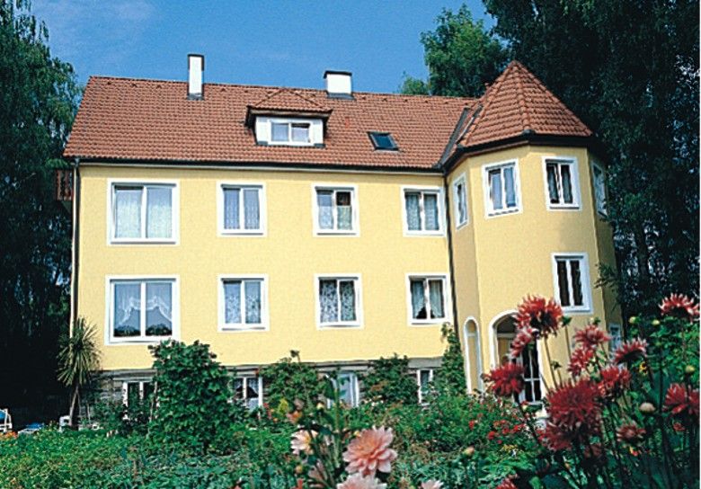 Yellow house with red roof and garden in the foreground.