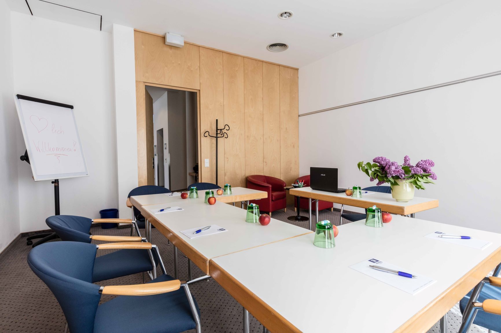 Conference room with tables, chairs, flipchart and flowers.