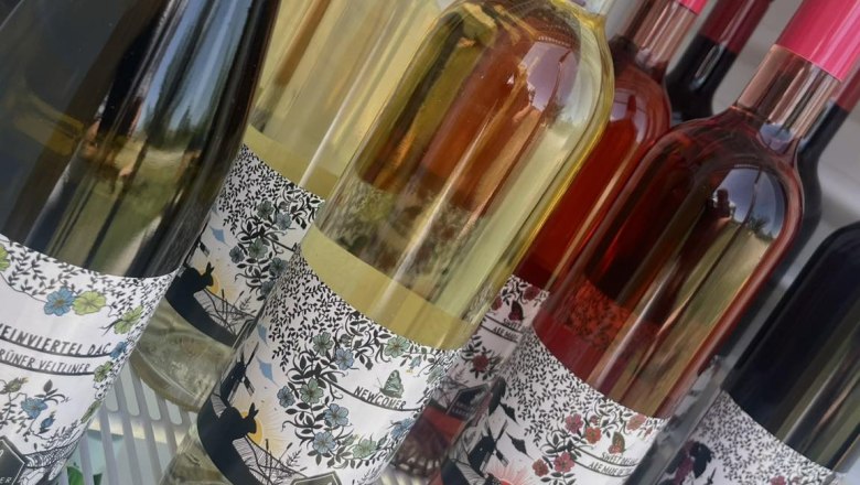 Wine bottles in a refrigerator with colorful labels.