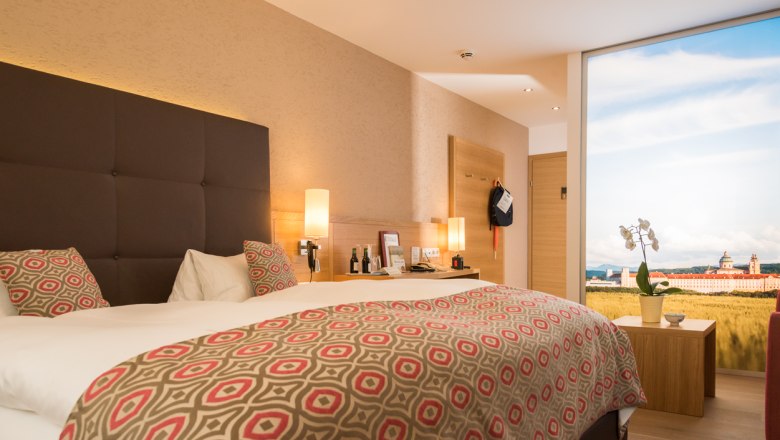 Modern hotel room with double bed, stylish lamps and large window with landscape view.