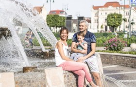 A smiling family sits by a fountain on Tulln's main square.