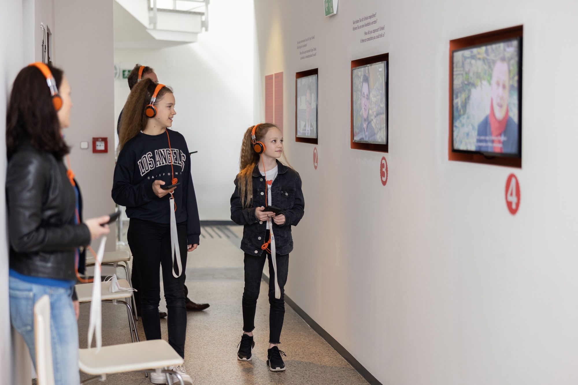 Visitors with headphones look at screens in a museum.