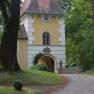 Historic building with tower and clock in a wooded area.