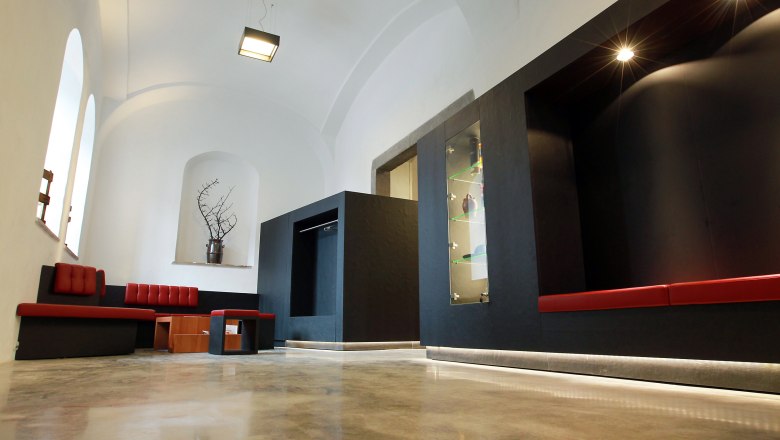 Modern interior with red benches and black walls.