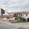 Exterior view of a building with red roofs and two flags in front of it.