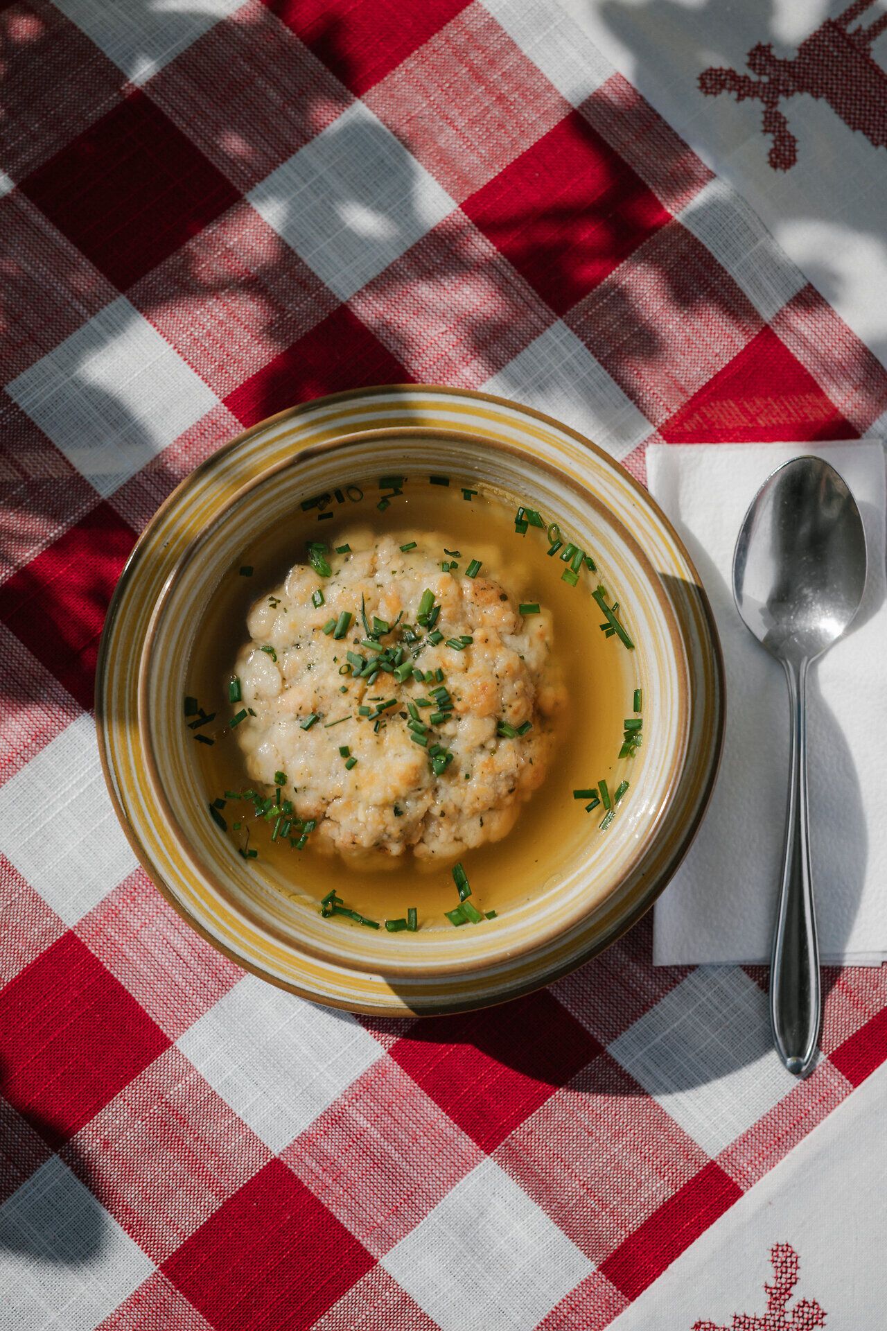 Clear soup with semolina dumplings on a plate on a checkered tablecloth at the Damböckhaus on Schneeberg