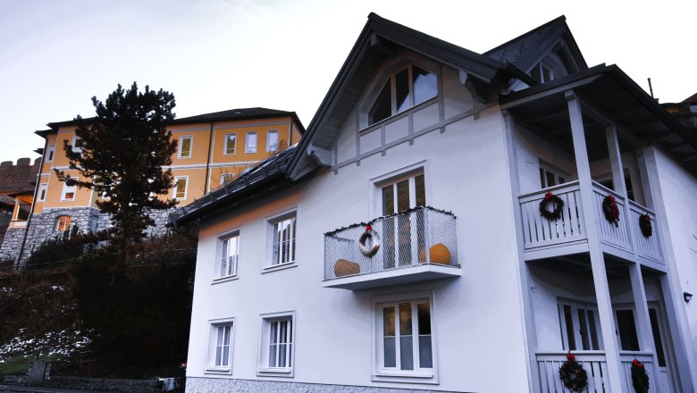 Two houses, one white with a balcony, the other yellow, with decoration.
