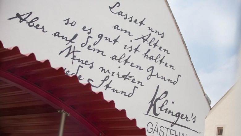 Fa&ccedil;ade of Klinger's guest house with handwritten inscription and red canopy.