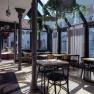Interior view of a modern caf&eacute; with glass roof and plants.
