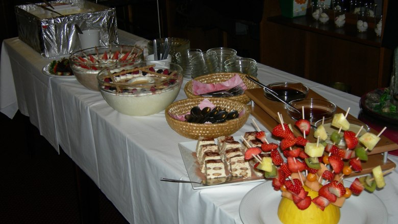 Buffet with desserts and fruit skewers on a table.