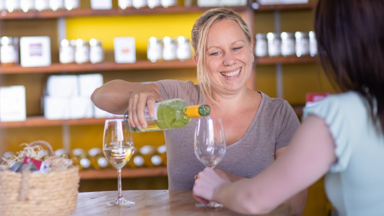 Woman pouring wine into a glass while smiling.