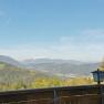 View from a restaurant balcony of a mountainous landscape with forest and a snow-covered peak in the background.