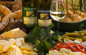 Heurigen snack with wine, cheese, bread and cold cuts on a table.