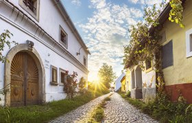 Cobblestone street in Röschitz with historic buildings and sunset.