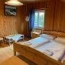Wood-paneled double room with bed, table, chair and window.
