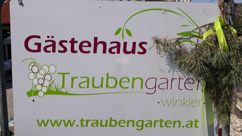 Sign with the inscription 'G&auml;stehaus Traubengarten Winkler' and website address, decorated with branches.