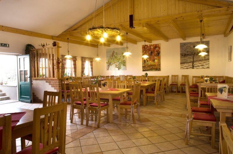 Interior view of a cozy wine tavern with wooden furniture and decorative paintings on the walls.