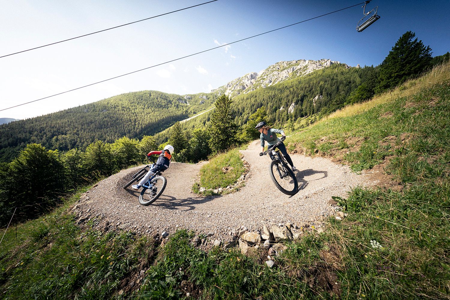 two bikers in the bike park in the background the Schneeberg with chairlift