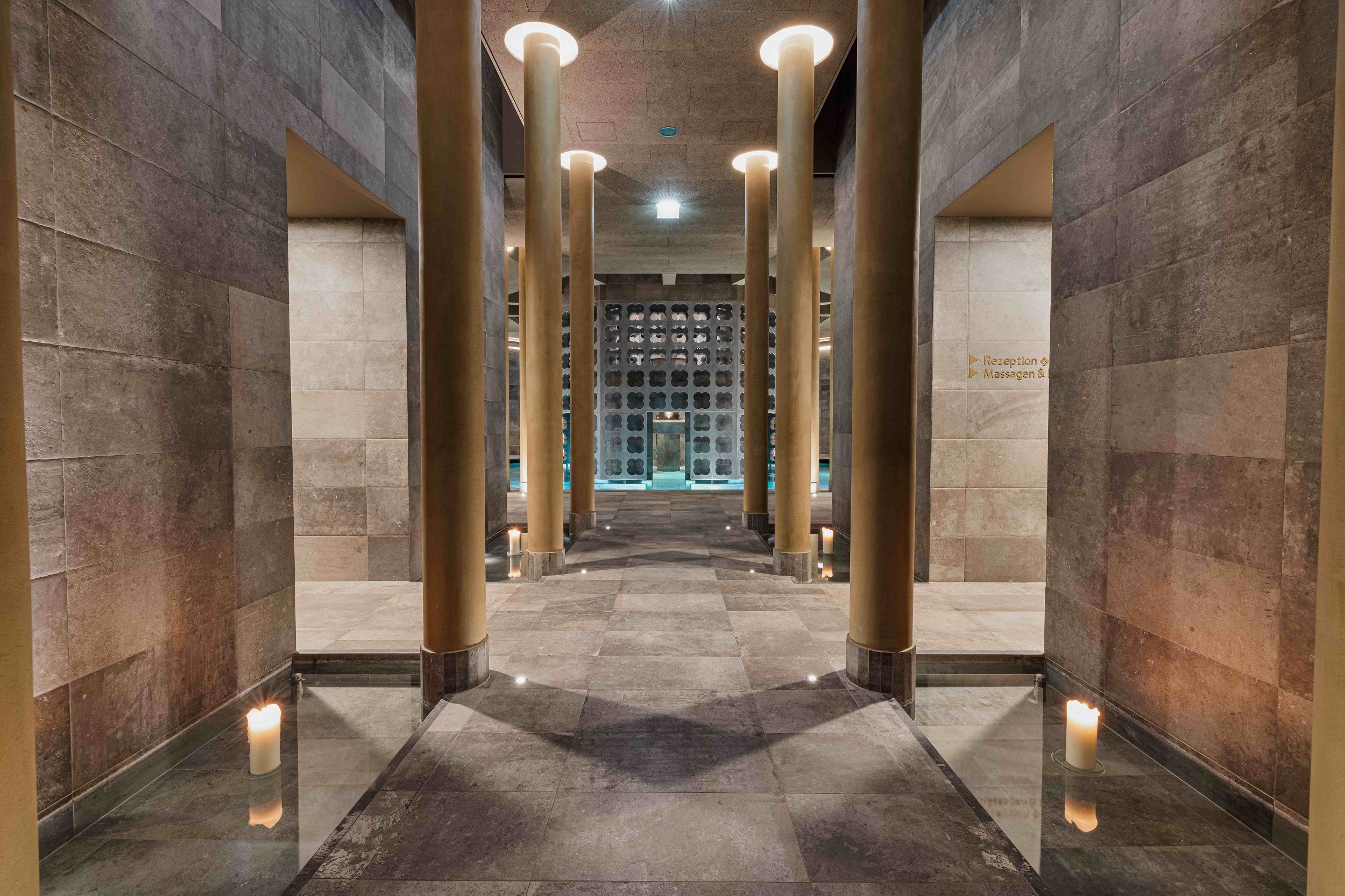 Interior view of a modern spa with high columns and candlelight.