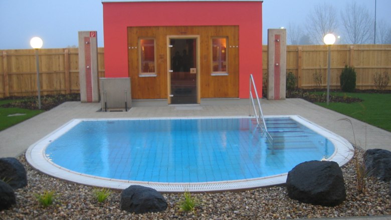 Exterior view of a sauna with a small pool and garden.